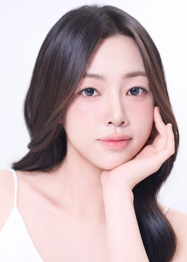 턱에 손을 댄 긴 머리 여성 모델(흰 민소매) — 수술 과목 카드(첫코성형)